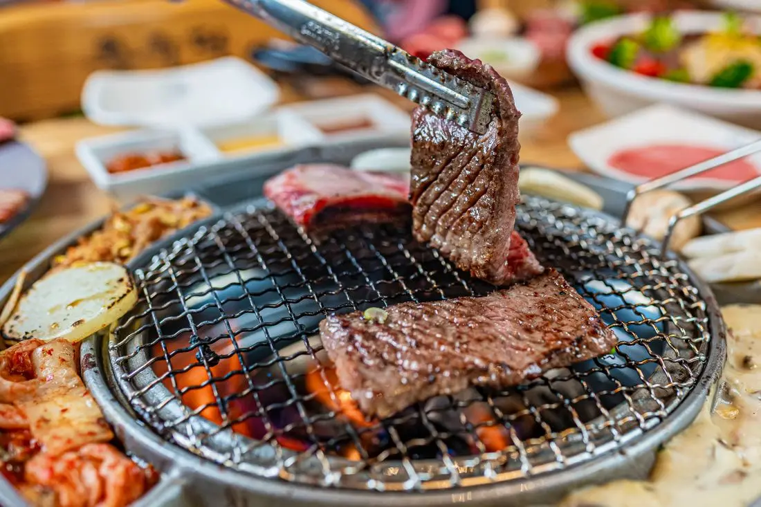 A Korean night-market vendor grilling street food over open flames